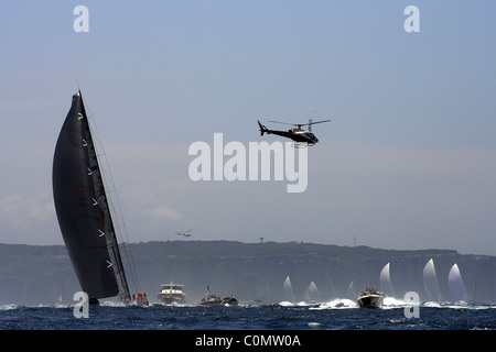 Maxi Wild Oats XI navigue dans la flottille de bateaux spectateurs et médias hélicoptères comme les chefs de la flotte le long de la côte. Banque D'Images