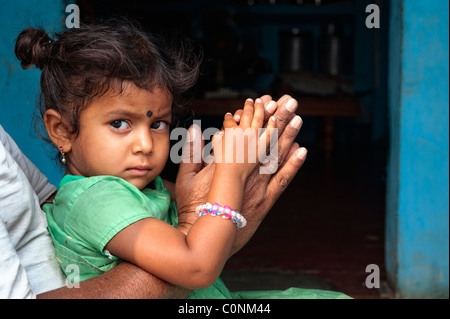 Indian girl sitting on granddads genoux en appui sur la prière les mains. L'Andhra Pradesh, Inde Banque D'Images