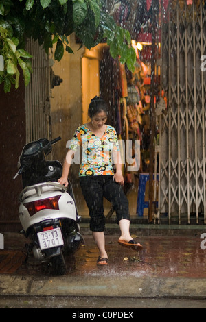 Vietnamienne à laver ses pieds dans l'eau de pluie Banque D'Images