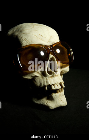 Un crâne en céramique portant des lunettes de soleil bon marché. Banque D'Images