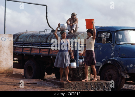 Deux des femmes de prendre de l'eau d'un puits comme un camion-citerne se remplit dans la région exposés à la sécheresse en dehors de Fortaleza, Brésil. Banque D'Images