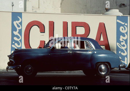 La Havane. Cuba. American Vintage voiture en face de slogan patriotique 'Viva Cuba Libre' dans la vieille Havane. Banque D'Images