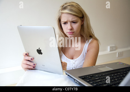 Blonde woman holding Apple iPad avec ordinateur portable, à la demande Banque D'Images