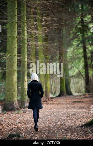 Jeune blonde modèle en noir stiletto chaussures et manteau d'hiver de marcher seul dans les bois en automne Banque D'Images