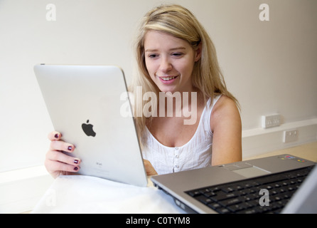 Blonde woman holding Apple ipad et également à l'aide d'un ordinateur portable Banque D'Images