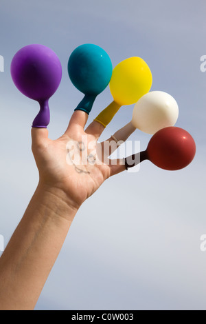 Visage dessiné sur une main avec des ballons de couleur sur les doigts Banque D'Images