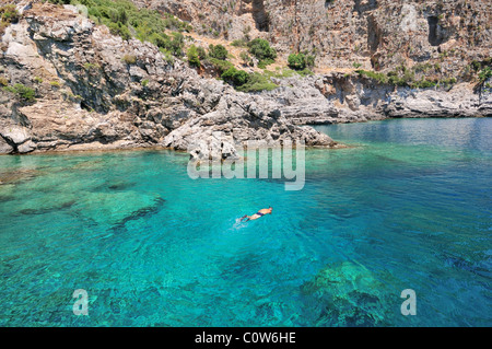 Un plongeur nage en eaux de mer cristalline, entouré par la magnifique côte sauvage, Turquie Banque D'Images