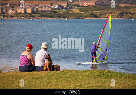 D'âge mûr assis regardant un windsurfer à Portland tandis que leur chien regarde la direction opposée Banque D'Images