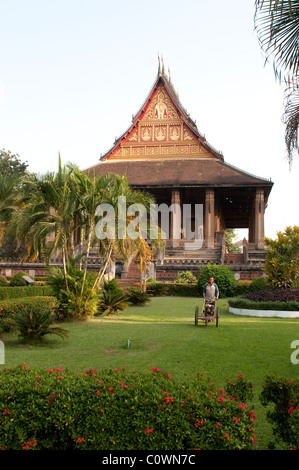 Tondre la pelouse jardinier, Haw Phra Kaew, maintenant un musée d'art et d'antiquités, Vientiane, Laos Banque D'Images