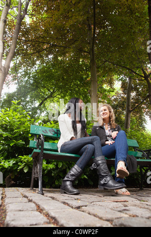 Portrait de deux jeunes femmes détendue friends chatting in the park Banque D'Images