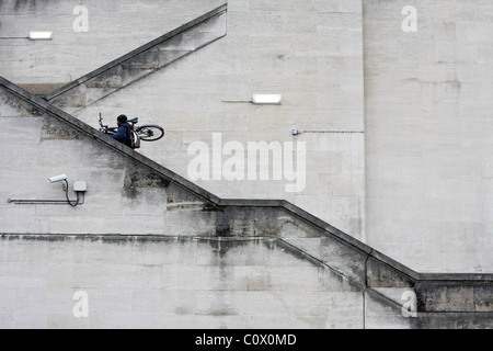 Un homme portant son vélo en haut d'un escalier menant au sommet de Waterloo Bridge à Londres, Angleterre Banque D'Images