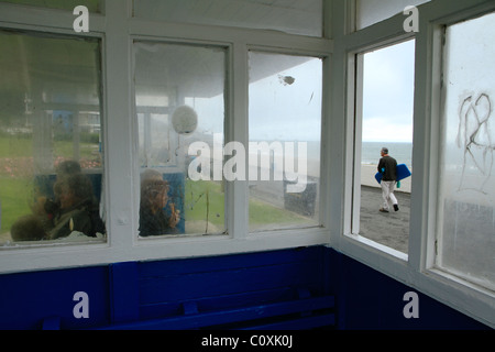 L'homme passe devant l'abri du front, Westward Ho ! Devon, UK Banque D'Images