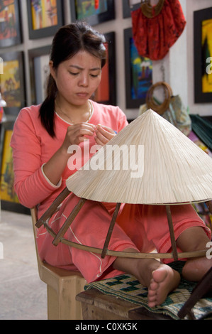 L'Asie, Vietnam, Da Nang. Ancienne capitale impériale de Hue. Woman making local vietnamien typique en forme de chapeaux coniques en bambou. Banque D'Images