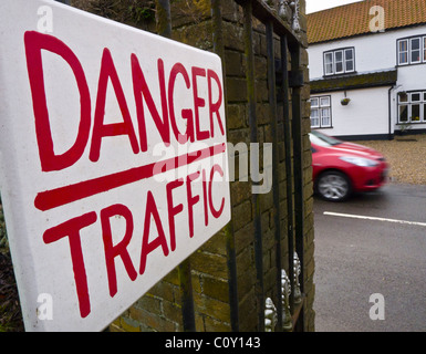 Un panneau d'avertissement "Danger" Lecture de la circulation avec une voiture en mouvement sur la route derrière Banque D'Images