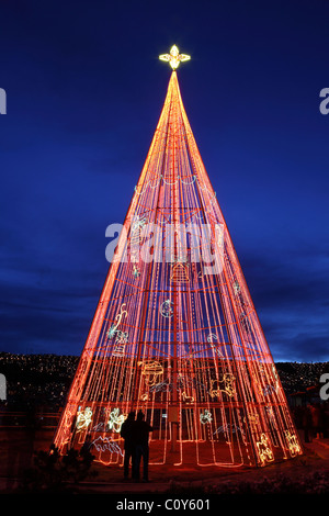 Les gens regardent un arbre de Noël artificiel fait de bandes lumineuses rouges à la Paz, Bolivie Banque D'Images