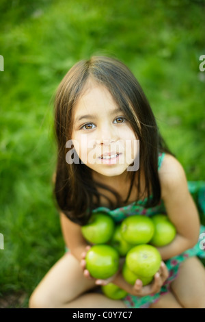 Fillette de six ans est assis sur pelouse et détient la pomme verte Banque D'Images