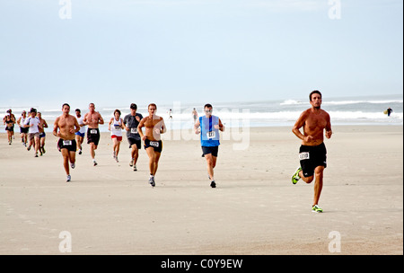 Porteur de couler le long de la plage, dans une course à l'océan sur le sable à Jacksonville Beach, Floride Banque D'Images