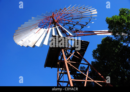 Lames de moulin argentées baignées de soleil sur un ciel bleu foncé, Barcaldine, Queensland, Australie. Banque D'Images