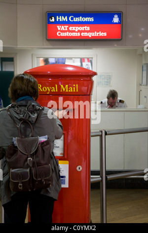 Passagère posts une enveloppe dans une boîte aux lettres de la poste à l'aéroport Heathrow de Londres. UK Banque D'Images