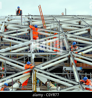 Équipe de travailleurs de l'industrie de la construction de sites de haute visibilité veste casques de sécurité occupés à travailler sur la nouvelle partie de toit de la station Kings Cross Londres Angleterre Royaume-Uni Banque D'Images