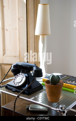 Ancien téléphone en bakélite rotatif sur le côté table avec des cactus en pot et lampe Banque D'Images