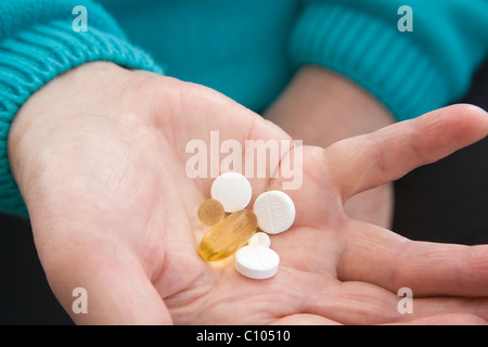 Close up femme âgée maintenant une sélection de médicaments Les médicaments sur ordonnance et sans ordonnance comprimés et capsules Banque D'Images