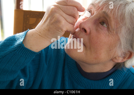 Close up femme âgée en mettant l'histamine anti des gouttes pour soulager les symptômes de la fièvre des foins Banque D'Images