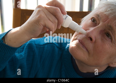 Close up femme âgée à l'aide d'un spray nasal pour soulager les symptômes de la fièvre des foins Banque D'Images