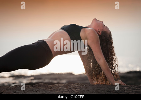 Jeune femme pratique le yoga sur la plage à Hawaii. Banque D'Images