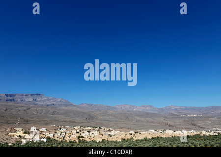 Le rouge, couleur de la terre maisons du village omanais de Al Hamra dans la montagnes Hajar, sous un ciel bleu azur. Banque D'Images