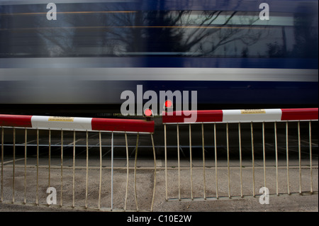 Train de banlieue rapide passe par les avions de passage à niveau automatique. Capture d'image avec une vitesse d'obturation lente pour montrer la vitesse du train. Banque D'Images