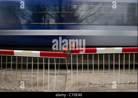 Train de banlieue rapide passe par les avions de passage à niveau automatique. Capture d'image avec une vitesse d'obturation lente pour montrer la vitesse du train. Banque D'Images