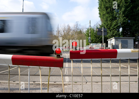 Train de banlieue rapide passe par les avions de passage à niveau automatique. Capture d'image avec une vitesse d'obturation lente pour montrer la vitesse du train. Banque D'Images