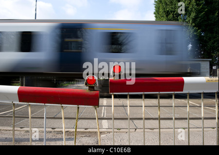 Train de banlieue rapide passe par les avions de passage à niveau automatique. Capture d'image avec une vitesse d'obturation lente pour montrer la vitesse du train. Banque D'Images