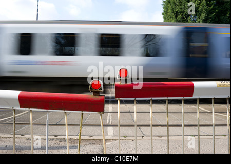 Train de banlieue rapide passe par les avions de passage à niveau automatique. Capture d'image avec une vitesse d'obturation lente pour montrer la vitesse du train. Banque D'Images