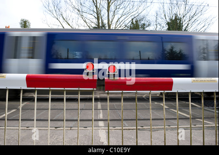 Train de banlieue rapide passe par les avions de passage à niveau automatique. Capture d'image avec une vitesse d'obturation lente pour montrer la vitesse du train. Banque D'Images