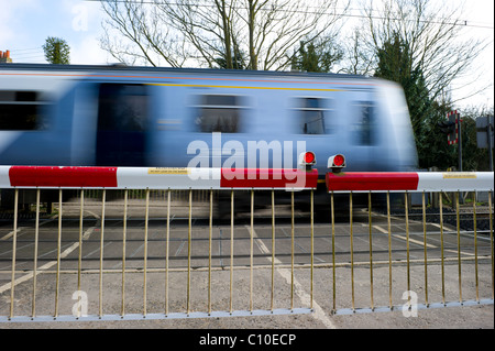 Train de banlieue rapide passe par les avions de passage à niveau automatique. Capture d'image avec une vitesse d'obturation lente pour montrer la vitesse du train. Banque D'Images