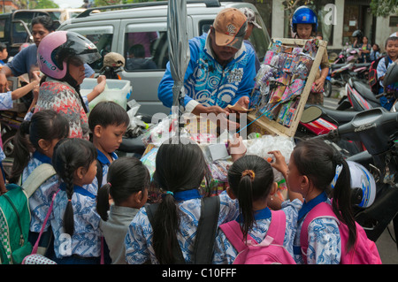 Les enfants de l'école primaire de l'Indonésie après l'école traite l'achat à un vendeur de rue à l'extérieur de l'école à Ubud, Bali, Indonésie Banque D'Images
