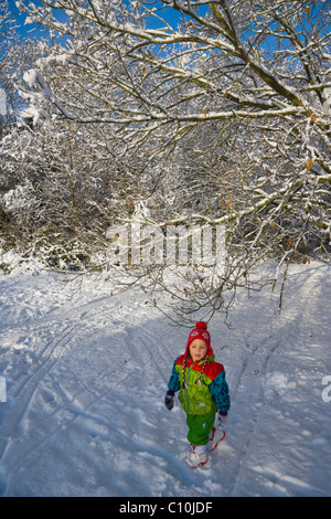 Petite fille qui marche dans la neige, Burghfield Common, Reading, Berkshire, Angleterre, Royaume-Uni, Europe Banque D'Images