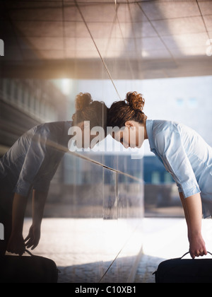 Mid adult femme italienne claque sa tête contre un mur à l'extérieur de bâtiment de bureaux. Banque D'Images