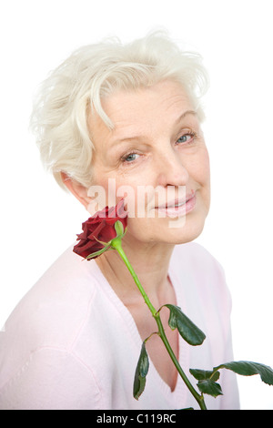 A young woman holding a le flétrissement rose rouge à son visage Banque D'Images