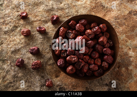 Baies de jujube (ziziphus jujuba) dans un bol de cuivre sur une surface en pierre Banque D'Images