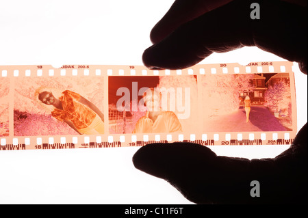 Photographe examinant une bande de film négatif couleur 35mm sur une boîte à lumière Banque D'Images