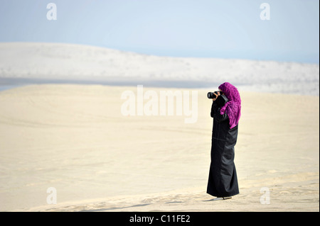 Photographe, femme arabe en costume traditionnel avec abayah et voile, Plage de Khor Al Udeid, Khor El Deid, Mer Intérieure Banque D'Images