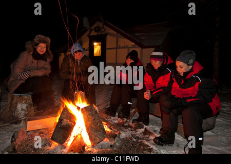 Les gens assis à un feu de camp, allumé wall tente, cabine derrière, Territoire du Yukon, Canada Banque D'Images