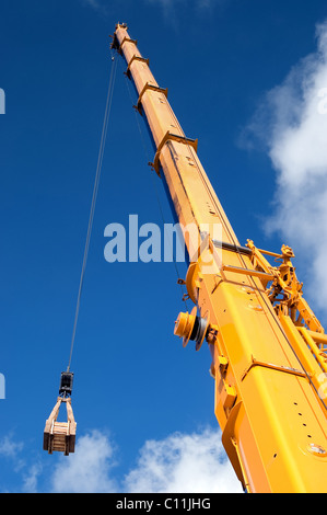 Grue mobile jaune de la rampe de chargement hydraulique soulève contre un ciel bleu Banque D'Images