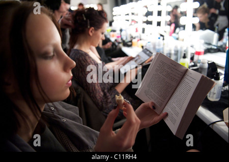 Un modèle lit un livre de Stephen Fry en se disant backstage avant l'automne 2011 collection rapide à Somerset House Banque D'Images