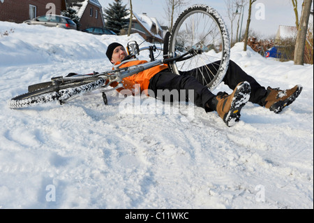 Un cycliste se brisant sur route glissante couverte de neige Banque D'Images