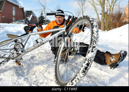 Un cycliste se brisant sur route glissante couverte de neige Banque D'Images