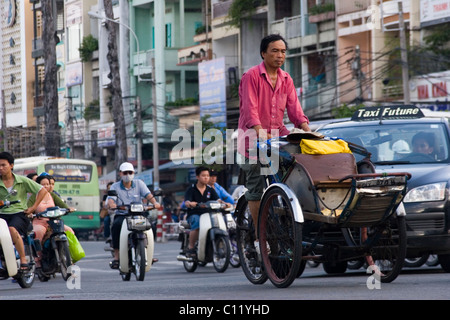 Un cyclo pilote est d'influence sur une rue bondée et occupé avec le trafic lourd à Saigon (Ho Chi Minh Ville) Vietnam. Banque D'Images